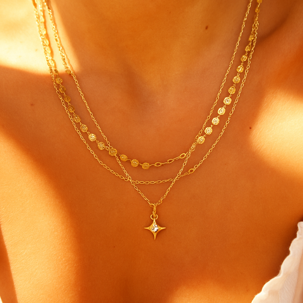 Close-up of a person wearing two gold necklaces with star pendants on a warm-toned background.