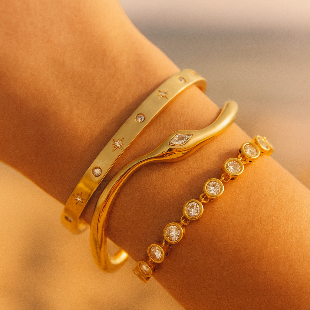 Gold bracelets with gemstones on a blurred natural background